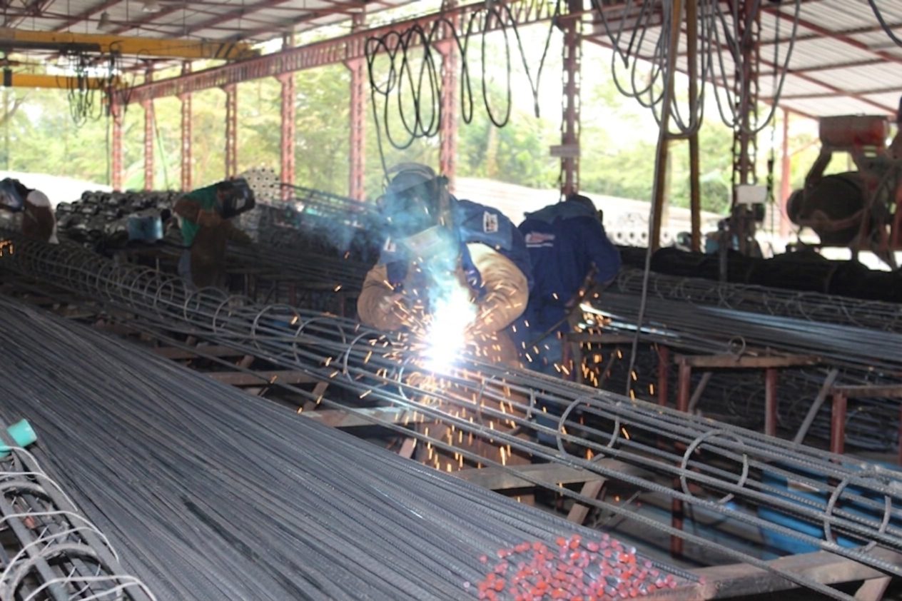 Soldadores armando la jaula de acero de postes de concreto centrifugado en la planta de PRECOLL S.A.S., Villavicencio, Meta